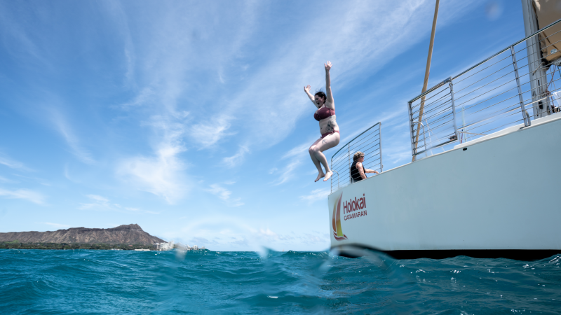 person jumping into the ocean from a catamaran