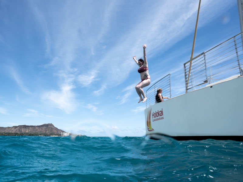 person jumping into the ocean from a catamaran